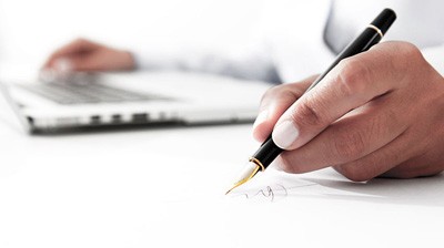 A person writing on paper with a pen.